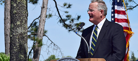 Director Ryder speaking at a podium outside